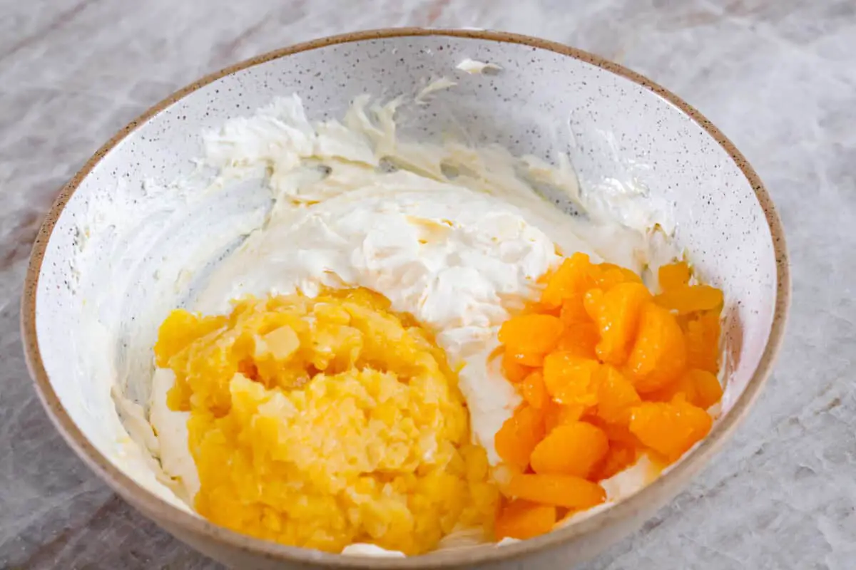 Third process photo of pineapple and mandarin oranges added to the pudding mixture. - Cookie Salad