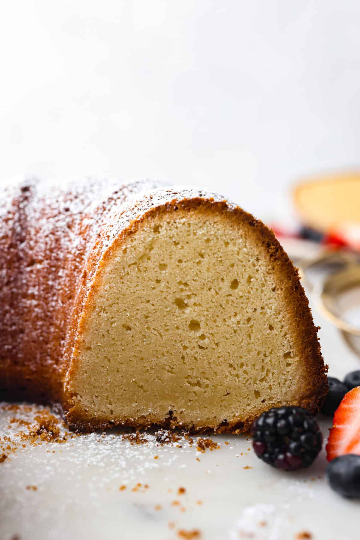 A bundt cake with a slice cut out of it so you can see the inside. - Cream Cheese Pound Cake