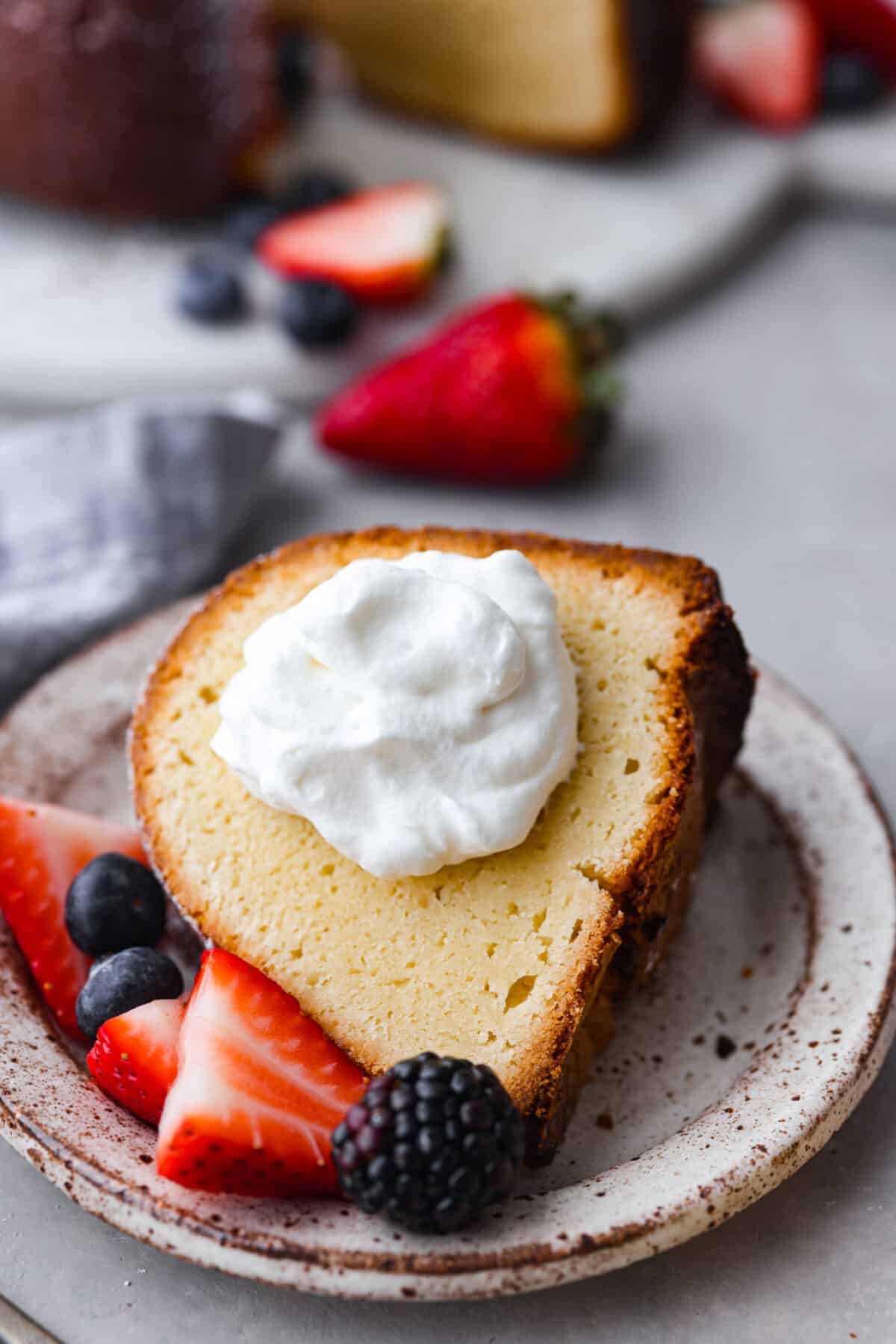 A slice of cake with a dollop of whipped cream on it. - Cream Cheese Pound Cake