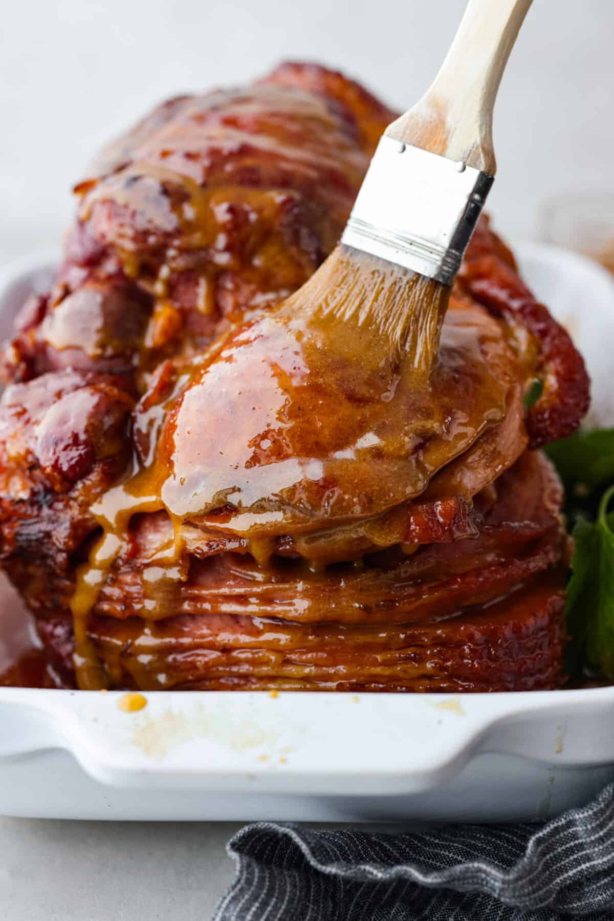 Honey glazed ham being basted with extras of the honey brown sugar mixture. - Classic Honey Glazed Ham