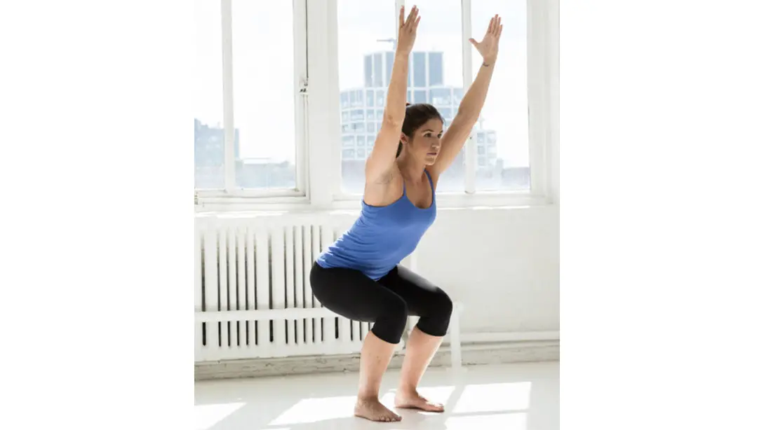 Fit woman performing yoga in a chair pose - 5 Best Yoga Poses Athletes Should Practice To Help Prevent Injuries
