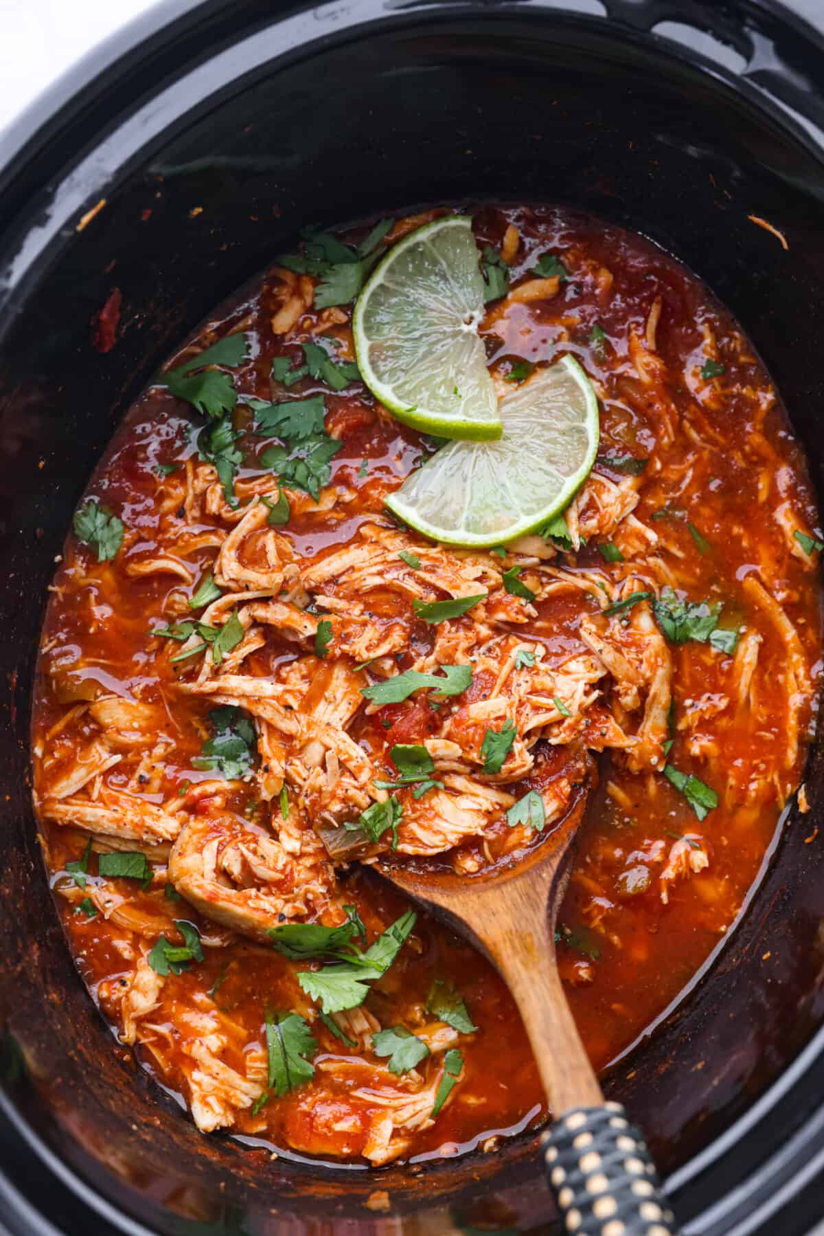Top view of salsa chicken in the crockpot with a serving spoon. - Crockpot Salsa Chicken