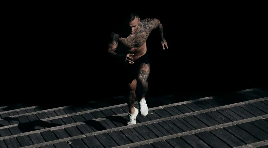 Fit man with tattoos running up the stairs at evening activities - Is There A Best Time Of Day To Exercise For Overall Health?