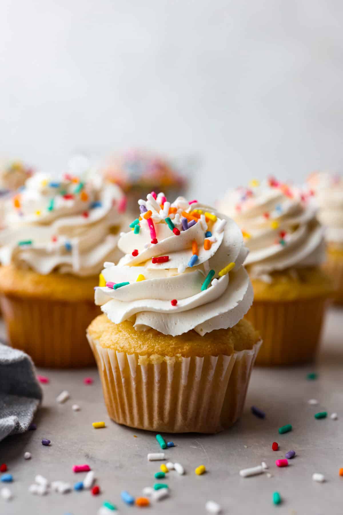 A cupcake frosted with meringue buttercream and topped with multicolored sprinkles - Swiss Meringue Buttercream