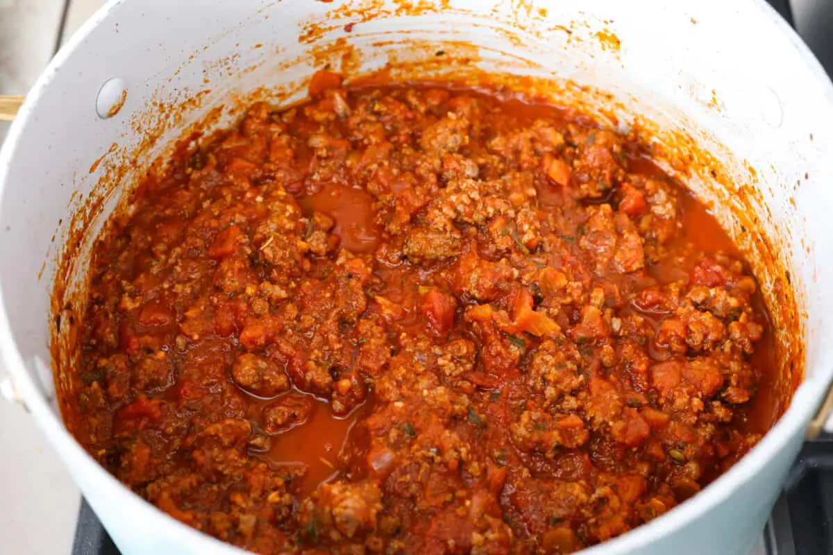 Marinara meat sauce simmering in a white pot being prepared to add to the sheet pan lasagna. - Easy Sheet Pan Lasagna