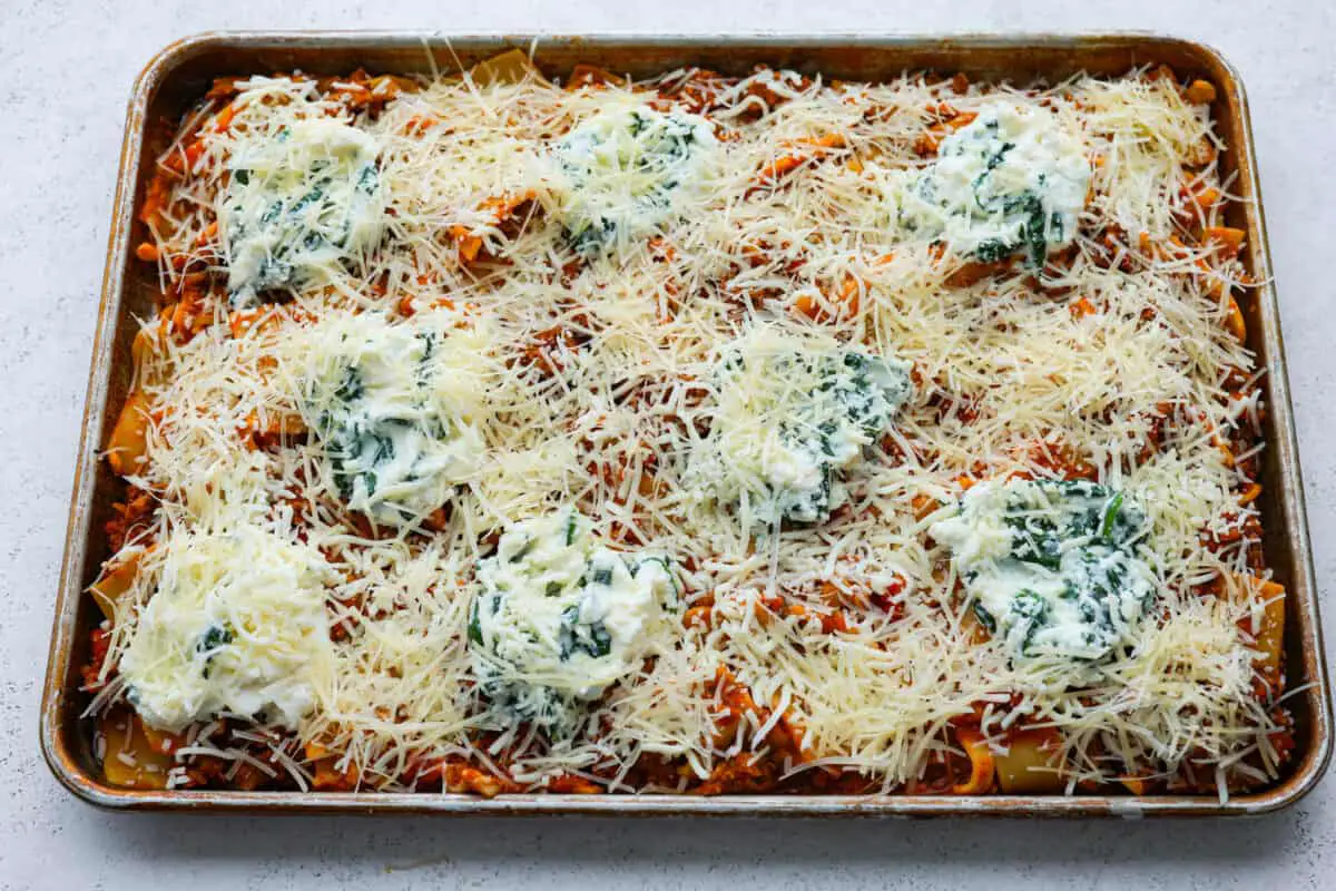 Shredded cheese sprinkled on top of sheet pan lasagna. - Easy Sheet Pan Lasagna
