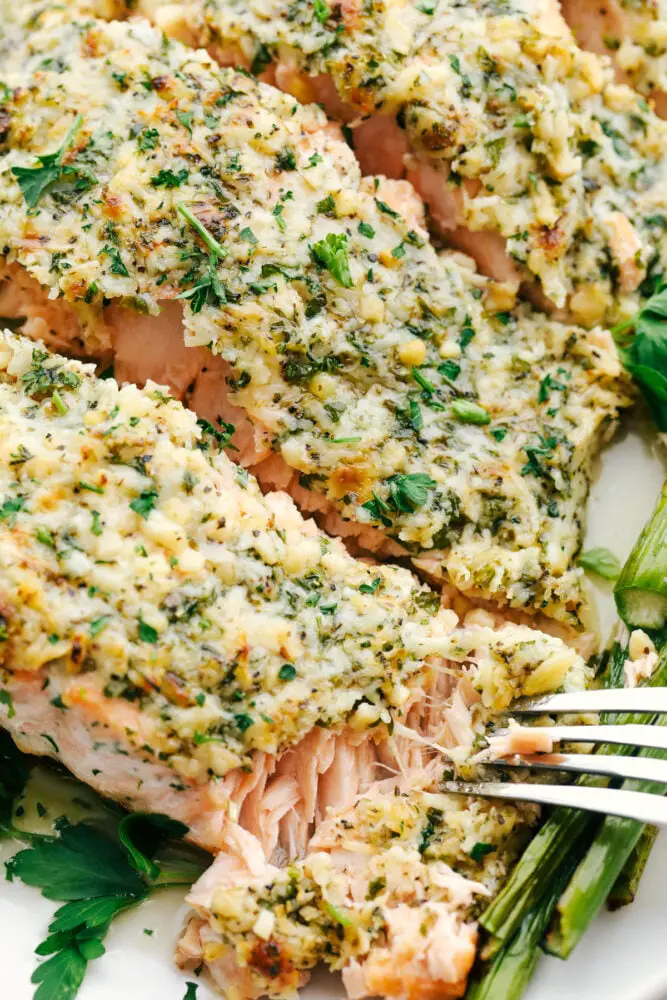 Using a fork to flake off a bite of salmon crusted with parmesan and garlic. - Baked Parmesan Garlic Herb Salmon In Foil