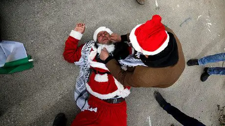 A man tends to a Palestinian protester, dressed as Santa Claus, after inhaling tear gas fired by Israeli troops during clashes in the West Bank city of Bethlehem, December 23, 2016. © Mussa Qawasma - Israeli Opposition Suggests Referendum After Calls To Annex West Bank — RT News