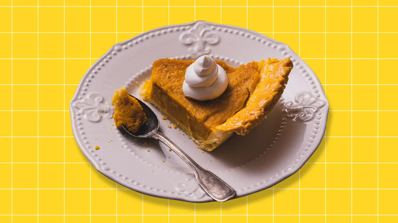 Piece of pumpkin pie on a white plate on a yellow background - Pumpkin Pie Lies: It’s Actually Canned Squash