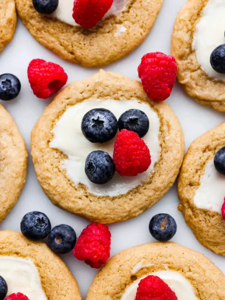 A zoomed in shot of a cheesecake cookie topped with blueberries and raspberries. - Cheesecake Cookies