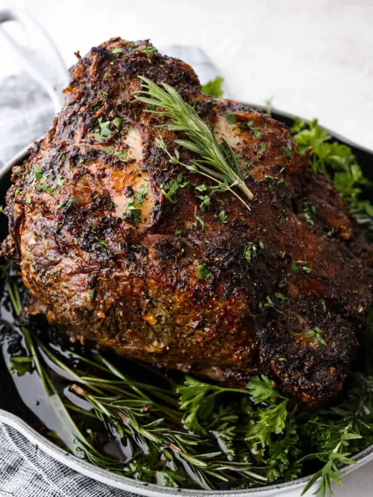 A cooked prime rib garnished with herbs. - Insanely Delicious Prime Rib Recipe