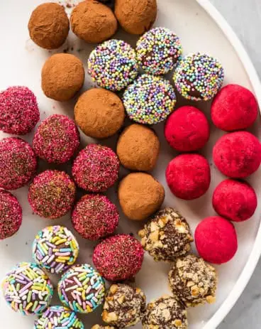 A white platter with multi-colored chocolate truffles. - Cream Cheese Mints