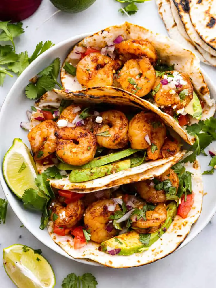 Top-down view of 3 prepared tacos on a white plate. - Easy Shrimp Tacos