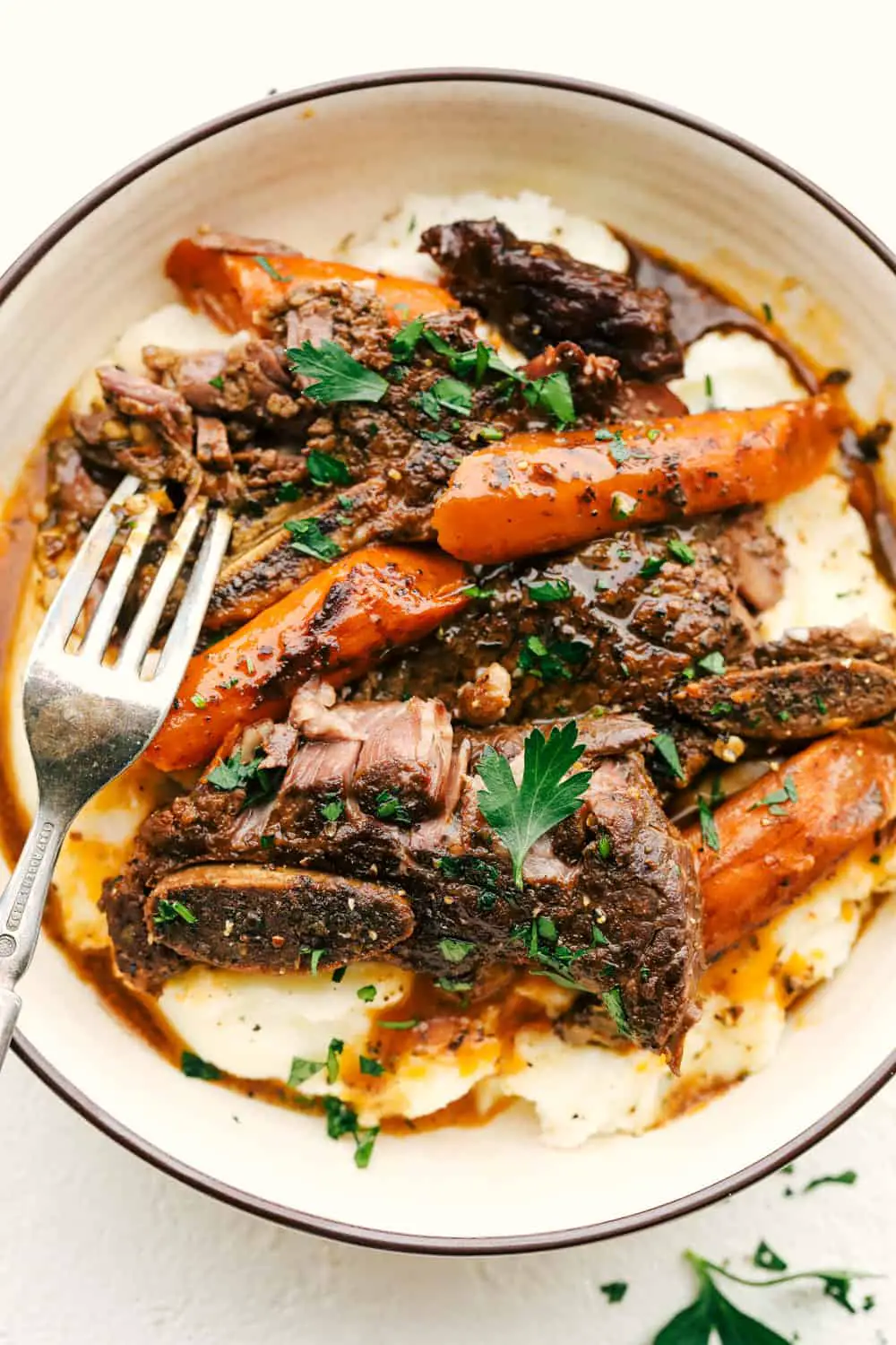 Fork Tender Slow Cooker Short Ribs in a bowl with mashed potatoes and carrots. - Fall Off The Bone Slow Cooker Short Ribs