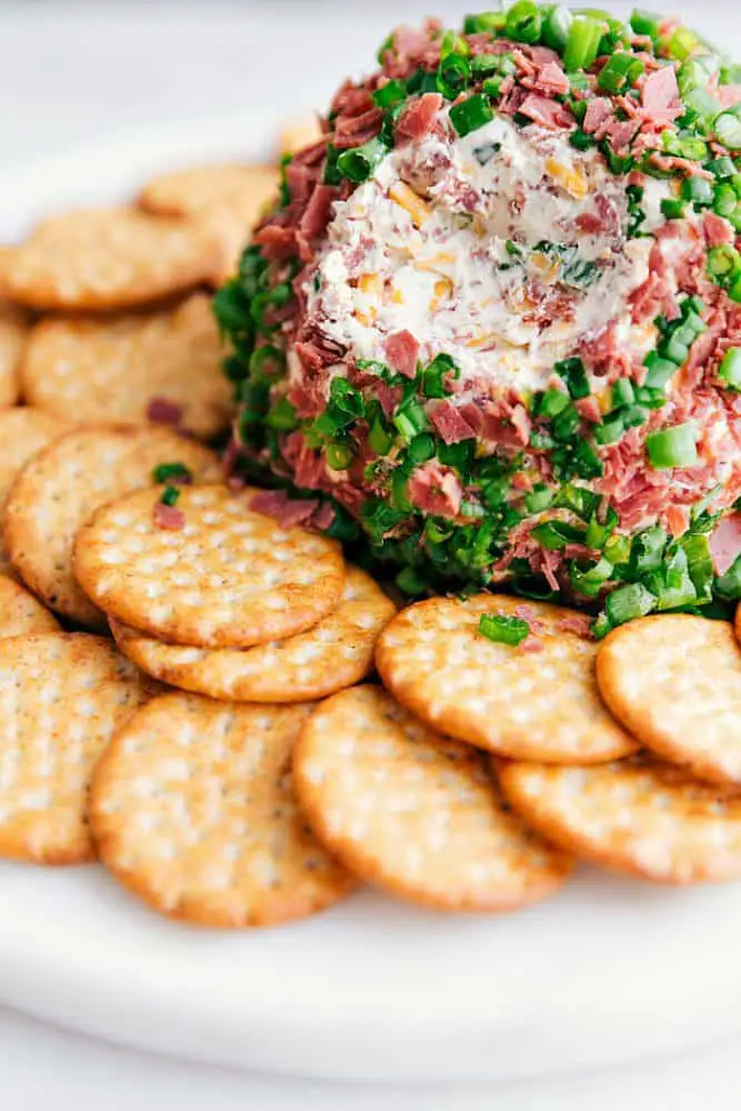 Chipped beef cheese ball on a white plate with crackers surrounding it. - Easy Chipped Beef Cheese Ball
