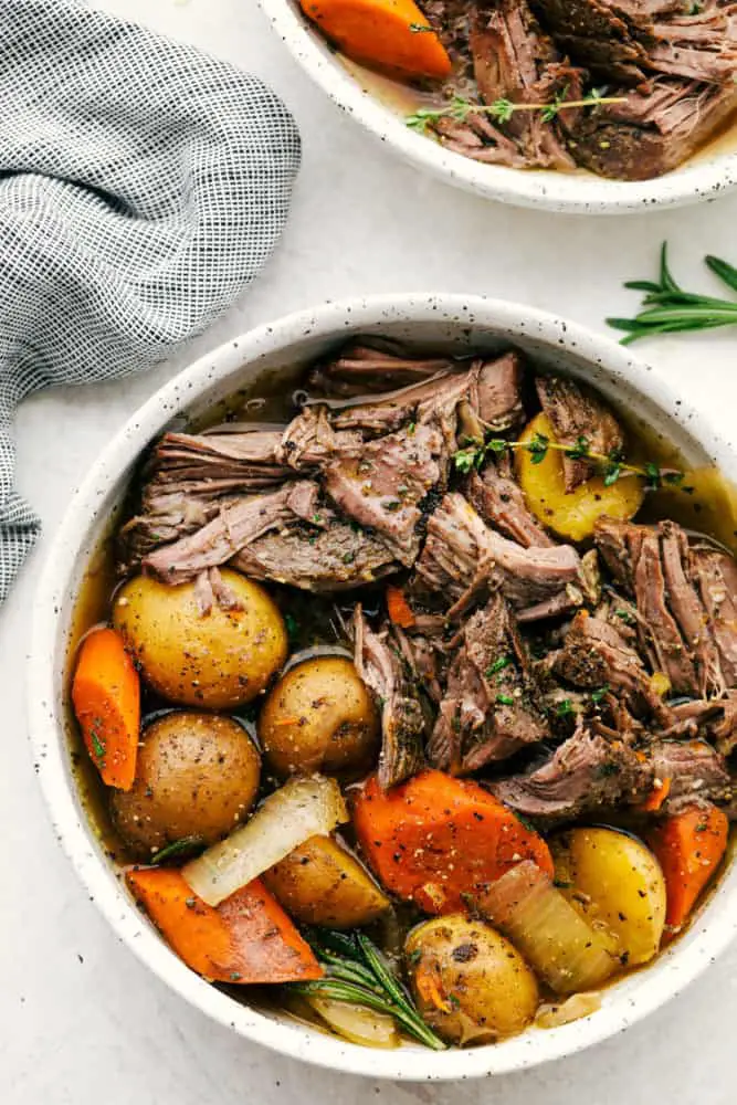 Shredded roast and vegetables served in a white bowl. - Melt In Your Mouth Pot Roast Recipe