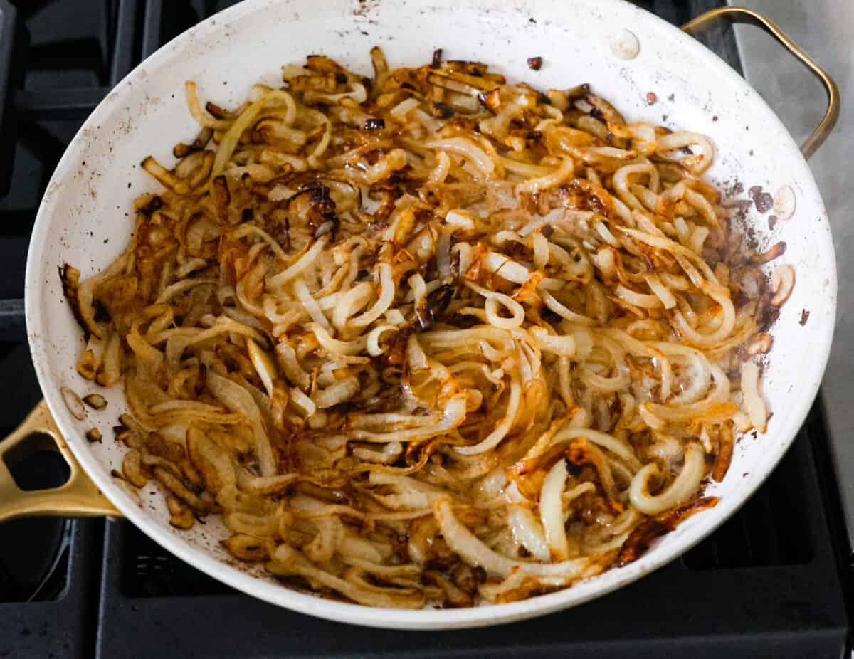 The first step, caramelizing the onions in a white skillet. - French Onion Pork Chops
