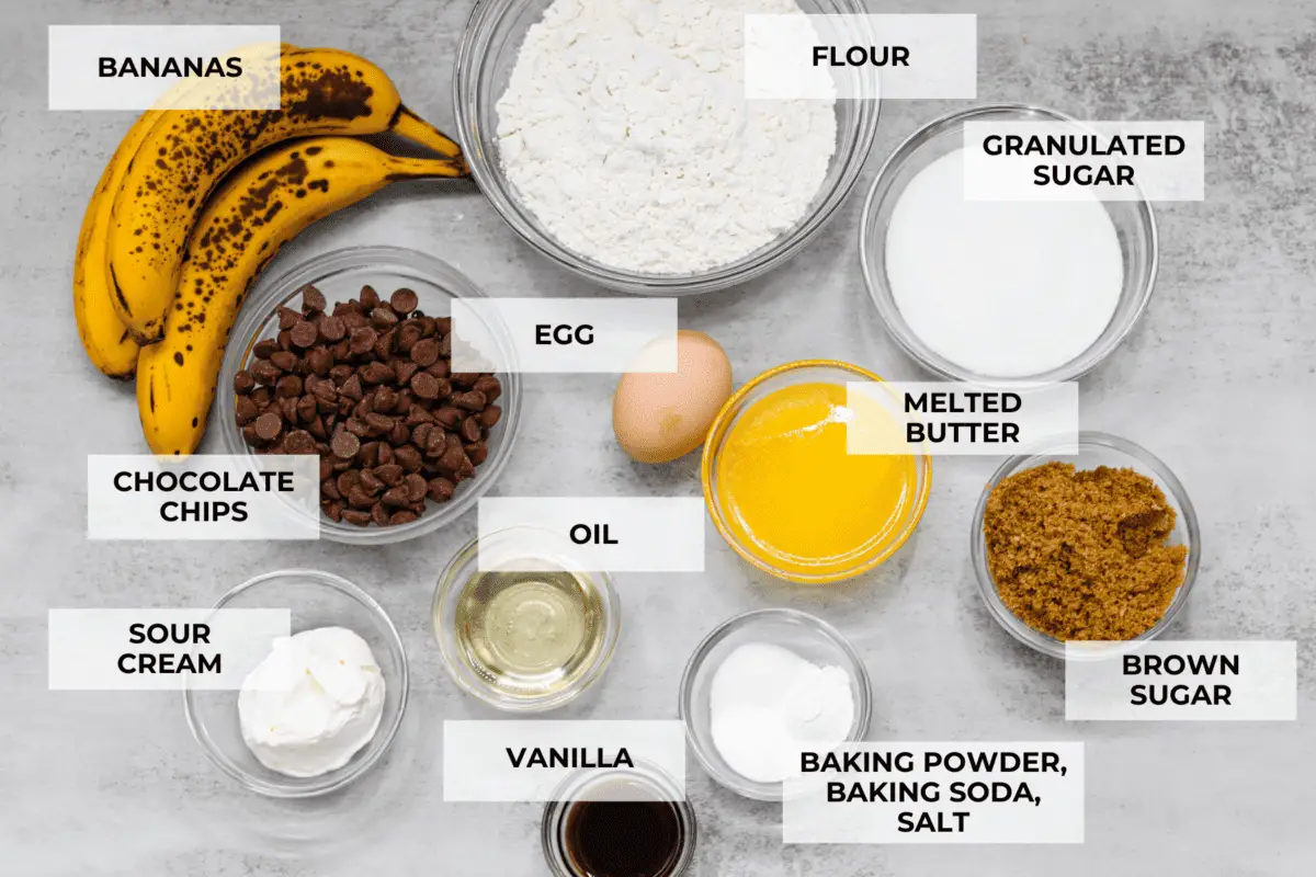 A top shot of ingredients for the muffins, all in glass bowls and labeled. - Banana Chocolate Chip Muffins