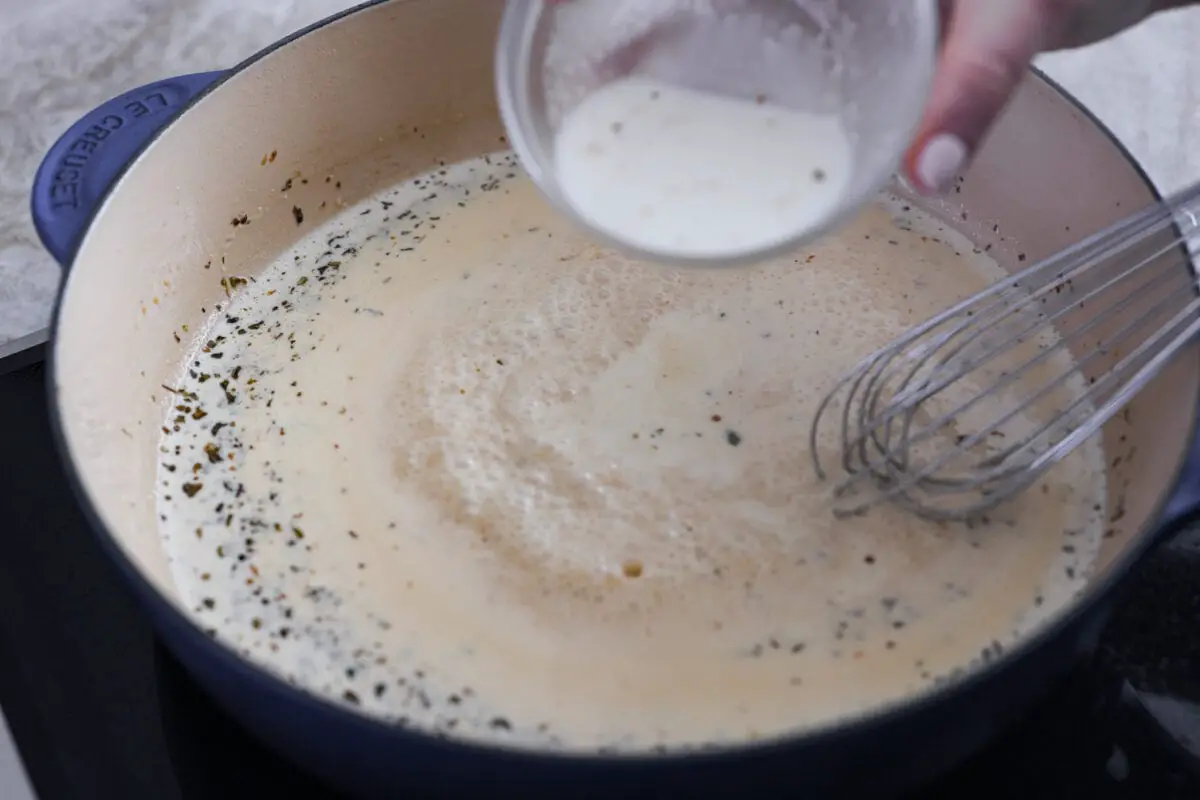 Adding the sauce ingredients to the skillet. - Creamy Lemon Parmesan Chicken