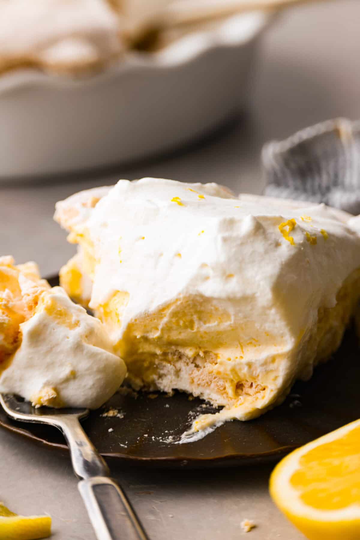 Close view of a slice of lemon pie on a plate with a fork. - Lemon Angel Pie